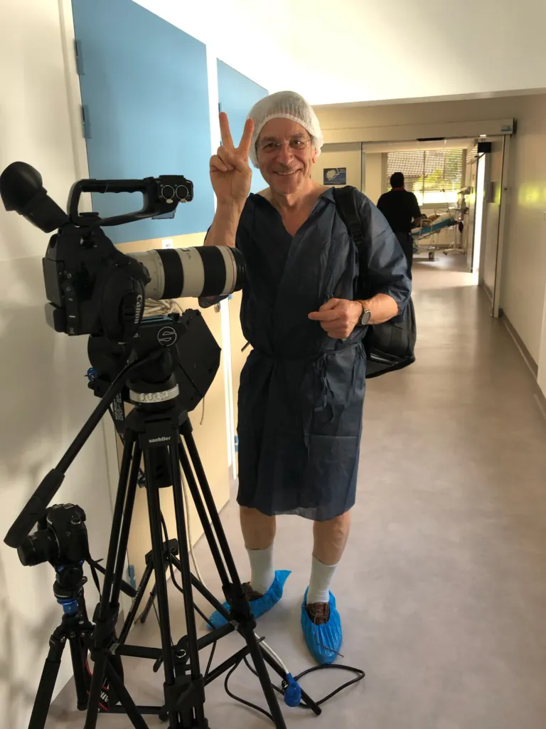 Membre de l'équipe en tenue de bloc opératoire, prêt à figurer le patient pour le tournage